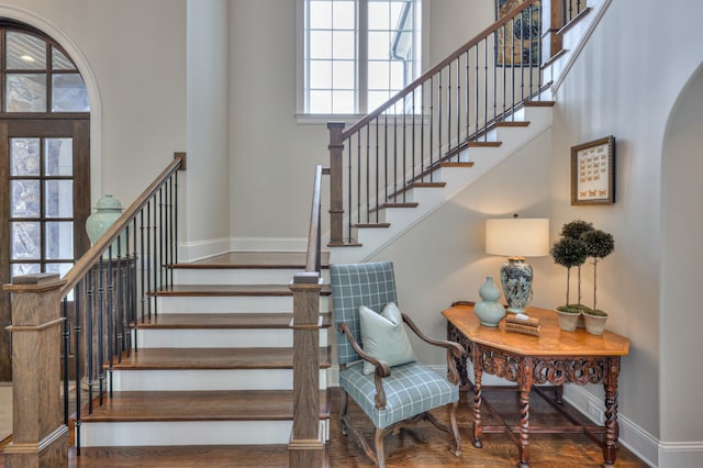 staircase featuring wood-type flooring and a towering ceiling