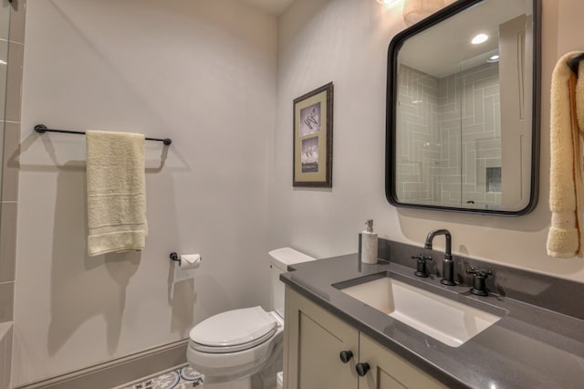 bathroom with vanity, tile patterned floors, toilet, and tiled shower