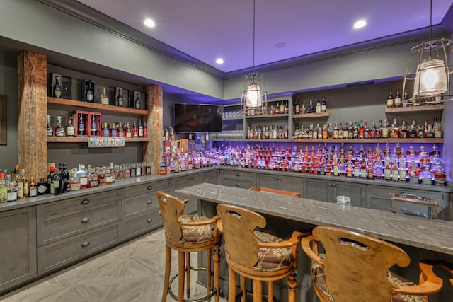 bar with crown molding, hanging light fixtures, stone counters, and gray cabinetry