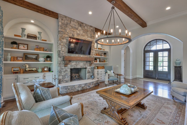 living room with built in shelves, beam ceiling, a chandelier, hardwood / wood-style flooring, and a fireplace