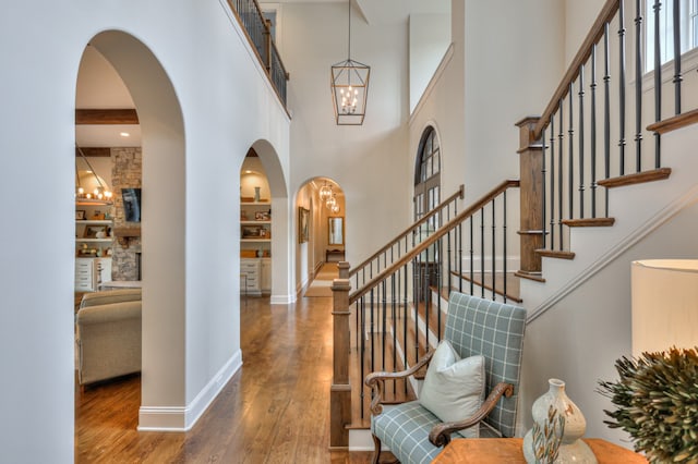 entryway featuring a notable chandelier, wood-type flooring, and a towering ceiling