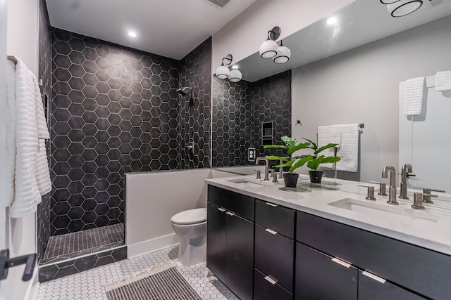 bathroom with vanity, tile patterned flooring, toilet, and tiled shower