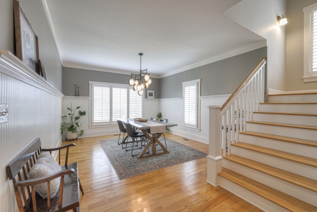 dining space featuring crown molding, light hardwood / wood-style flooring, and a notable chandelier