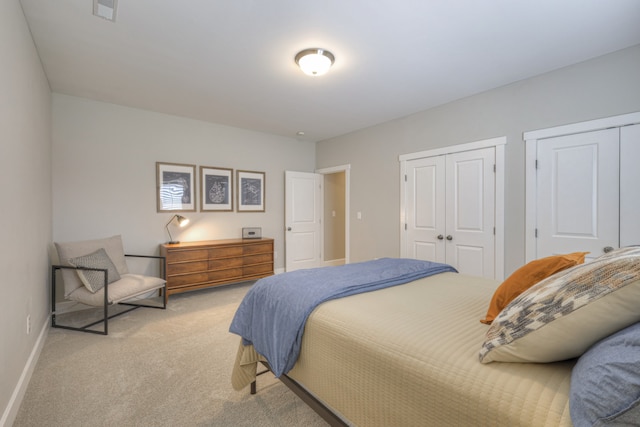 bedroom featuring light carpet and multiple closets