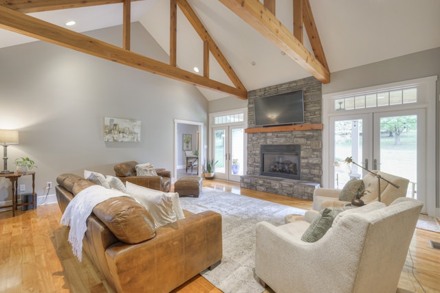 living room featuring high vaulted ceiling, a fireplace, light hardwood / wood-style flooring, and french doors