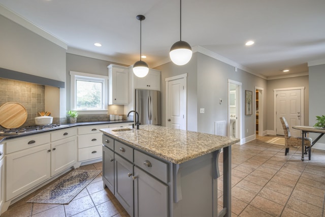 kitchen featuring dark stone counters, a kitchen island with sink, sink, white cabinetry, and appliances with stainless steel finishes