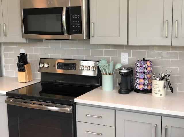 kitchen featuring decorative backsplash, stainless steel appliances, and white cabinets