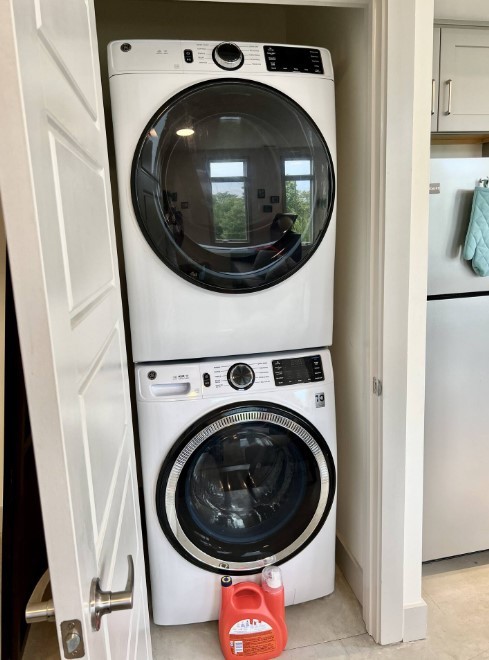 washroom featuring light tile patterned floors and stacked washing maching and dryer