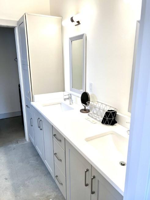 full bath with concrete flooring, double vanity, and a sink