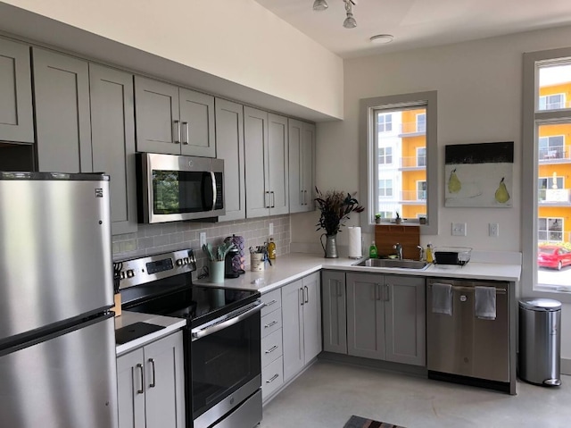 kitchen with gray cabinets, stainless steel appliances, backsplash, and sink