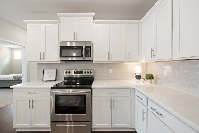 kitchen featuring decorative backsplash, stainless steel appliances, white cabinets, and dark hardwood / wood-style flooring