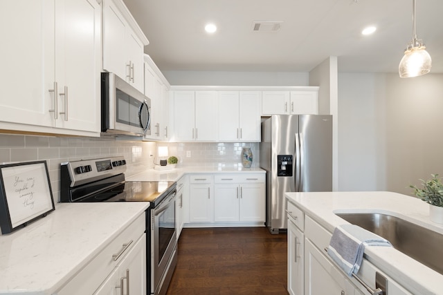 kitchen featuring white cabinets, pendant lighting, tasteful backsplash, stainless steel appliances, and dark hardwood / wood-style flooring