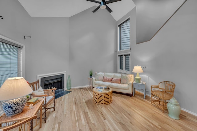 living room featuring ceiling fan, light hardwood / wood-style floors, and high vaulted ceiling