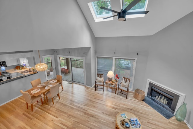 living room featuring ceiling fan, a skylight, high vaulted ceiling, and a wealth of natural light