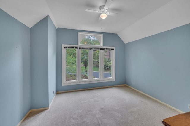 carpeted empty room with vaulted ceiling, ceiling fan, and plenty of natural light