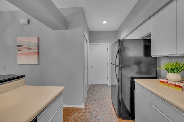 kitchen featuring white cabinetry and black fridge