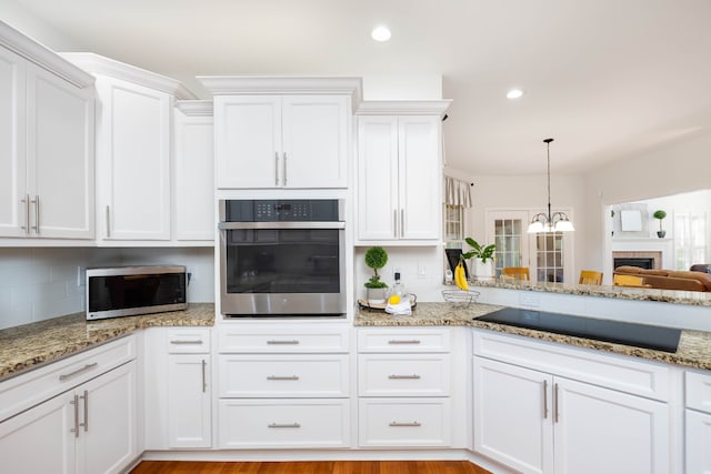 kitchen featuring white cabinets, appliances with stainless steel finishes, light wood-type flooring, and tasteful backsplash