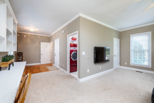 unfurnished living room with ceiling fan, crown molding, light carpet, and washer / dryer