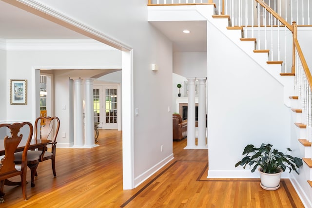 entrance foyer featuring light hardwood / wood-style flooring, crown molding, and ornate columns