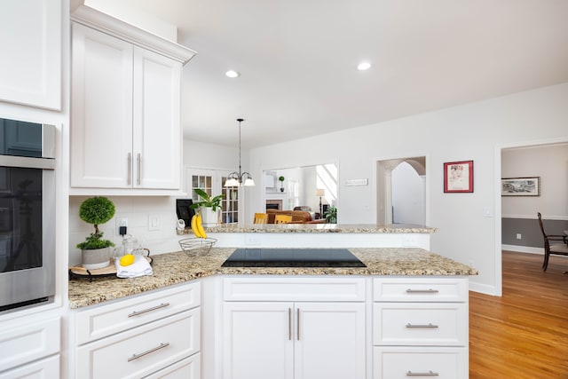 kitchen featuring white cabinets, kitchen peninsula, light wood-type flooring, and black electric stovetop