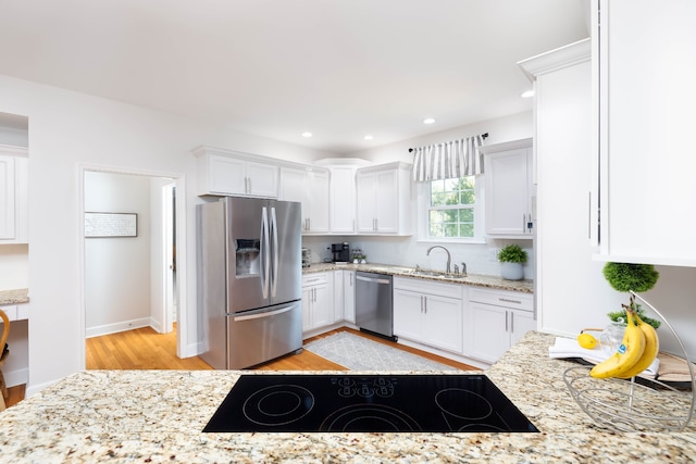 kitchen featuring appliances with stainless steel finishes, sink, light hardwood / wood-style flooring, and white cabinets