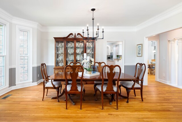 dining space with a notable chandelier, light wood-type flooring, and plenty of natural light