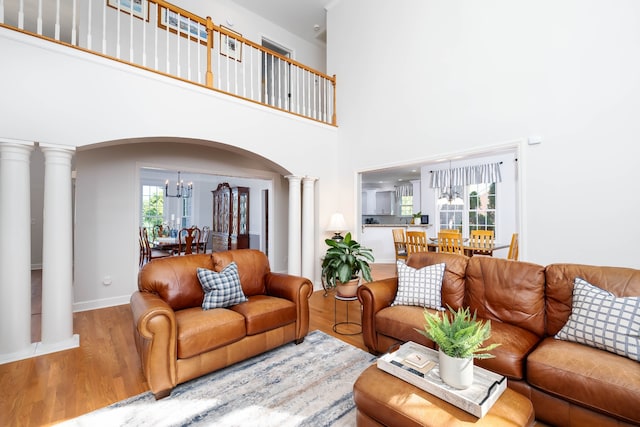 living room featuring ornate columns, a high ceiling, hardwood / wood-style floors, and a notable chandelier