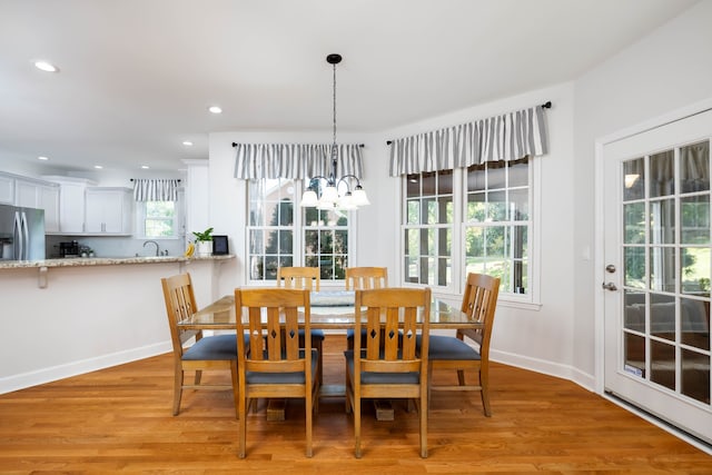 dining area with light hardwood / wood-style floors and an inviting chandelier