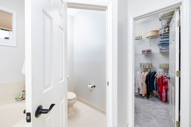 bathroom with a bathtub, toilet, and tile patterned floors