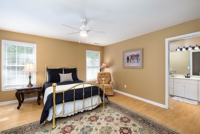 bedroom with ceiling fan, multiple windows, hardwood / wood-style floors, and connected bathroom