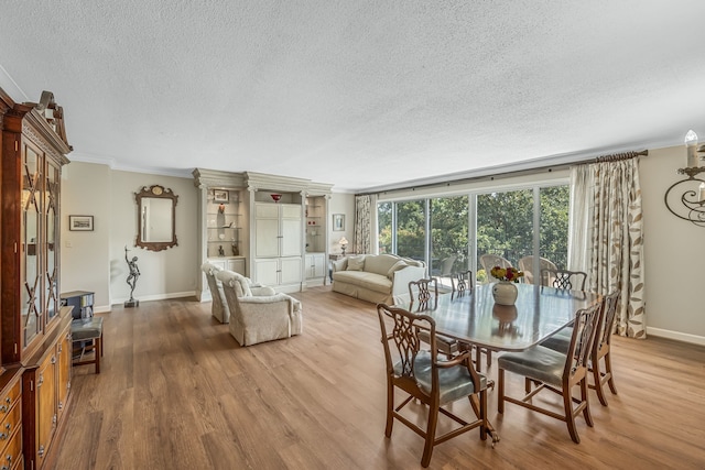 dining room featuring a textured ceiling, crown molding, and light hardwood / wood-style floors