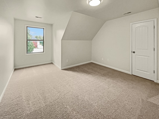 additional living space with light colored carpet and vaulted ceiling