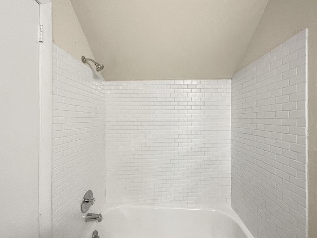 bathroom featuring tiled shower / bath combo and vaulted ceiling