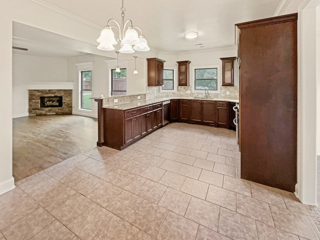 kitchen with tasteful backsplash, a stone fireplace, pendant lighting, an inviting chandelier, and sink