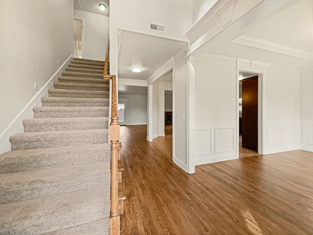 staircase with hardwood / wood-style floors and crown molding