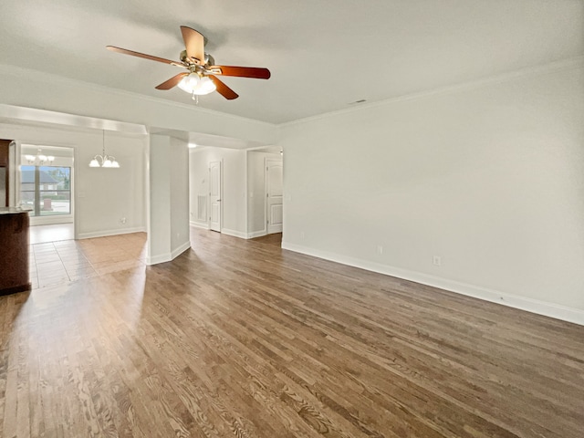 empty room with ceiling fan with notable chandelier, ornamental molding, and dark hardwood / wood-style flooring