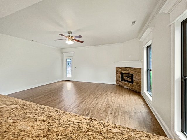 unfurnished living room with ceiling fan, a fireplace, dark wood-type flooring, and a healthy amount of sunlight