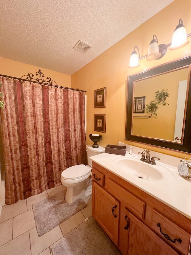 bathroom featuring vanity, toilet, a textured ceiling, walk in shower, and tile patterned flooring