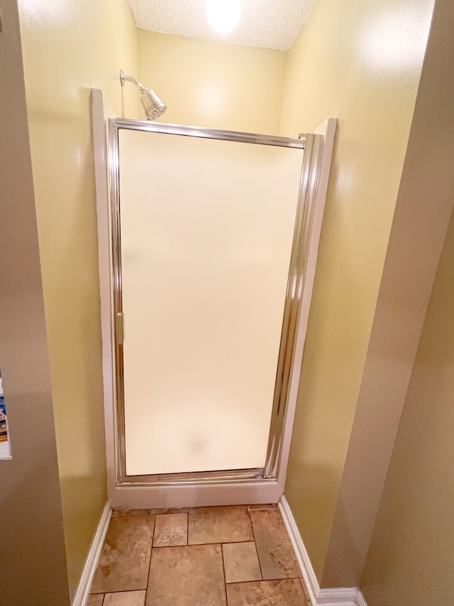 bathroom with a textured ceiling, tile patterned flooring, and a shower with door