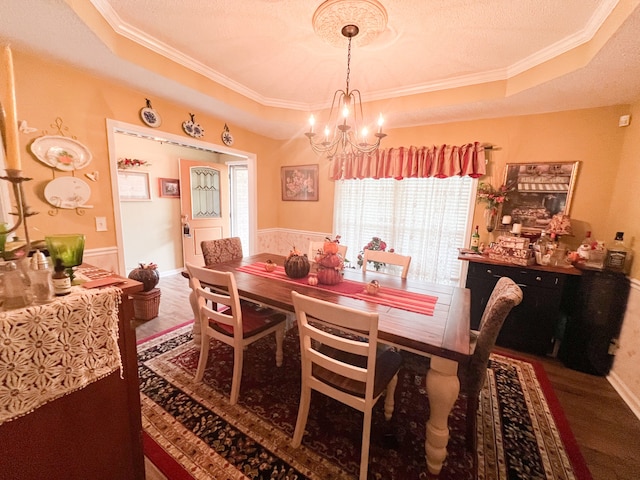 dining area featuring ornamental molding, a textured ceiling, hardwood / wood-style flooring, a tray ceiling, and an inviting chandelier