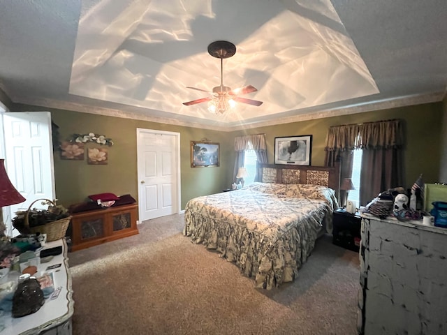 bedroom with carpet flooring, a tray ceiling, and ceiling fan