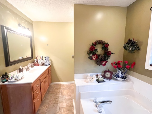 bathroom featuring a textured ceiling, a bathing tub, and vanity