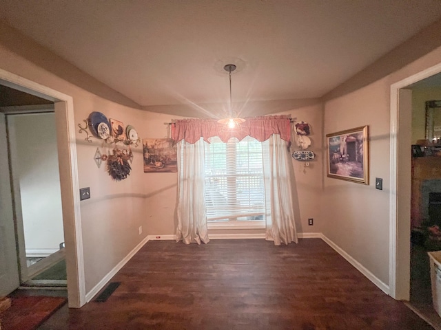 unfurnished dining area with an inviting chandelier and dark wood-type flooring