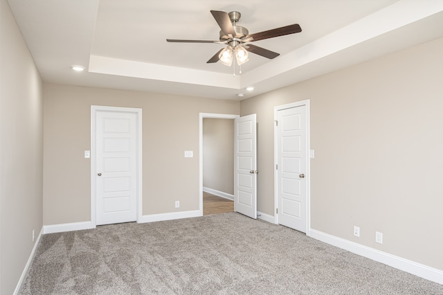 unfurnished bedroom with recessed lighting, a raised ceiling, carpet flooring, ceiling fan, and baseboards