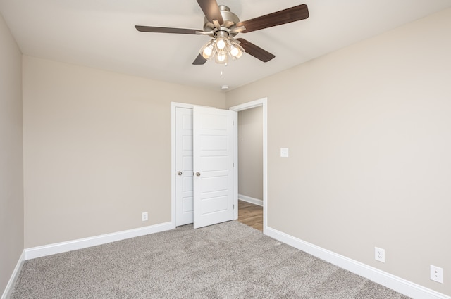 carpeted spare room with a ceiling fan and baseboards