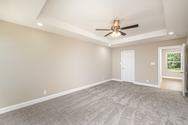 carpeted empty room with baseboards, a raised ceiling, a ceiling fan, and recessed lighting