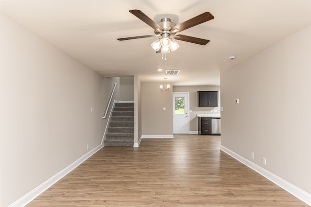 unfurnished living room featuring ceiling fan, wood finished floors, visible vents, baseboards, and stairs