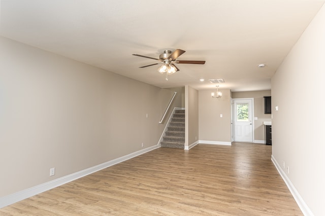 spare room featuring light wood-type flooring, visible vents, baseboards, and stairs