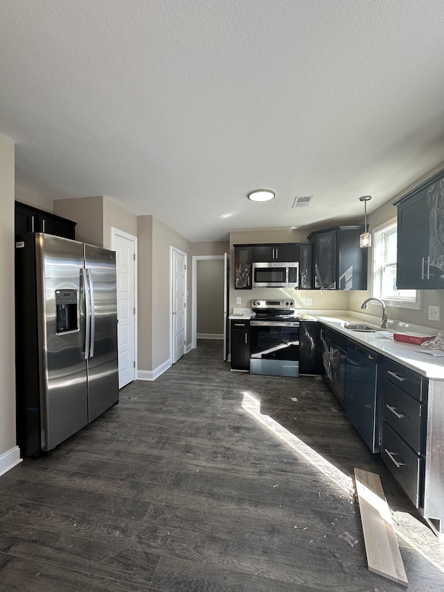 kitchen featuring sink, decorative light fixtures, a textured ceiling, appliances with stainless steel finishes, and dark hardwood / wood-style flooring