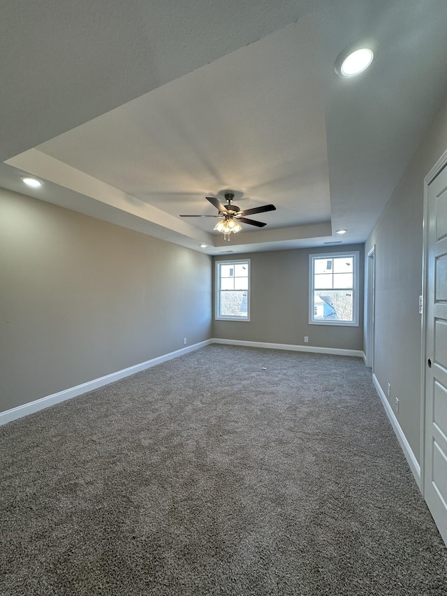 carpeted empty room featuring ceiling fan and a raised ceiling